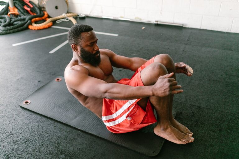 Mann macht Bauchübungen auf einer Matte im Gym – Sit-ups gegen Bauchfett