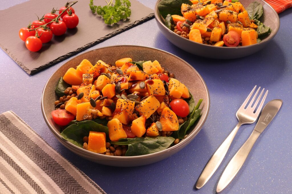 Schüssel mit Linsen, Spinat, Kürbis, Kirschtomaten und Kürbiskernen – eisenreiche pflanzliche Lebensmittel