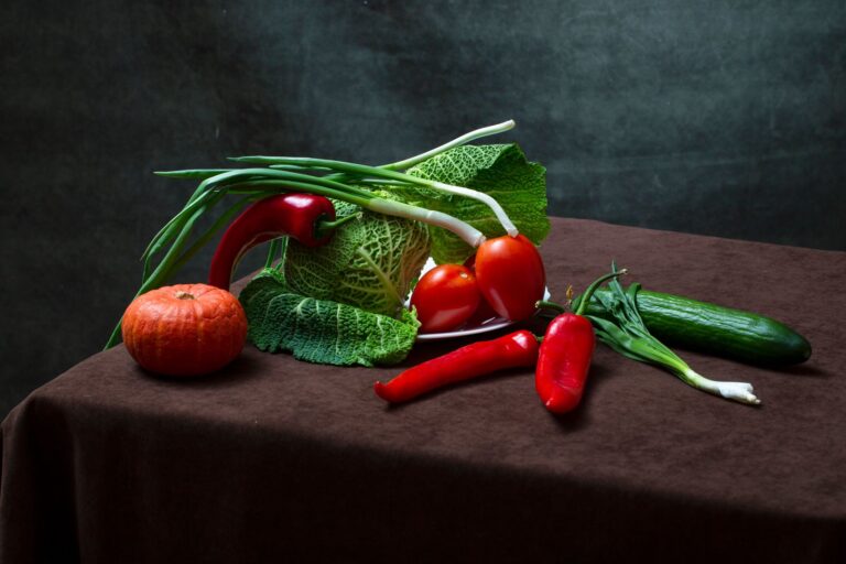 Frisches Gemüse auf einem Tisch: Wirsing, Tomaten, Kürbis, Paprika und Frühlingszwiebeln als kaliumreiche Lebensmittel