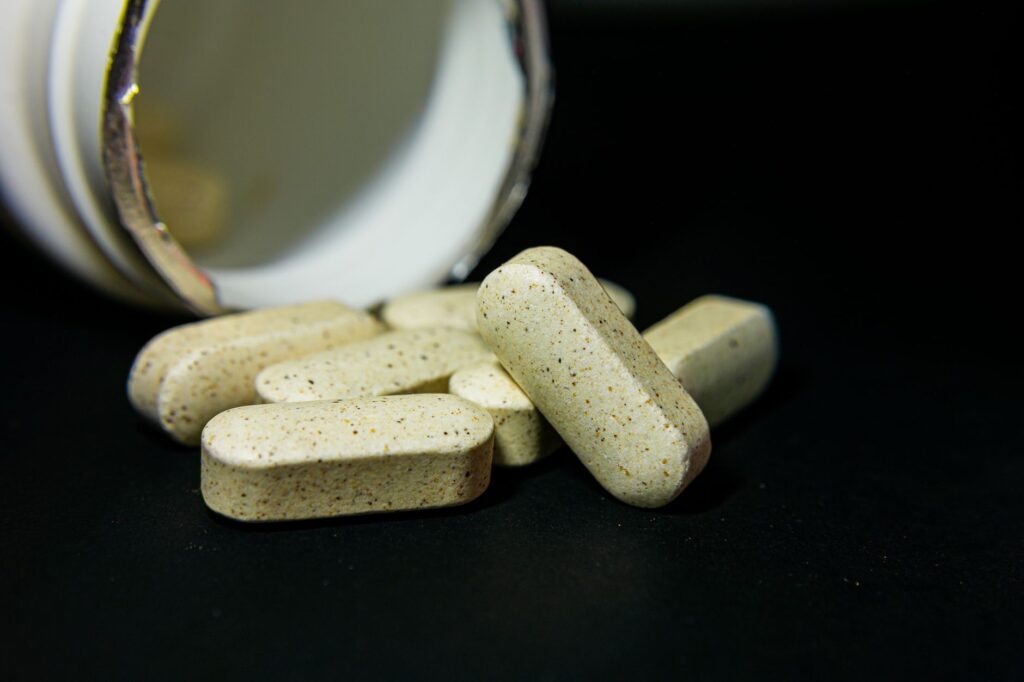 Magnesiumtabletten neben einem Glas Wasser auf einem Holztisch