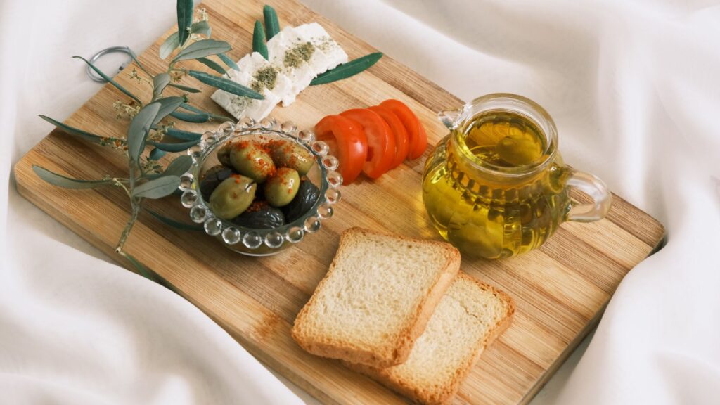 Mediterrane Lebensmittel auf einem Tisch: Gemüse, Olivenöl, Fisch und Vollkornbrot