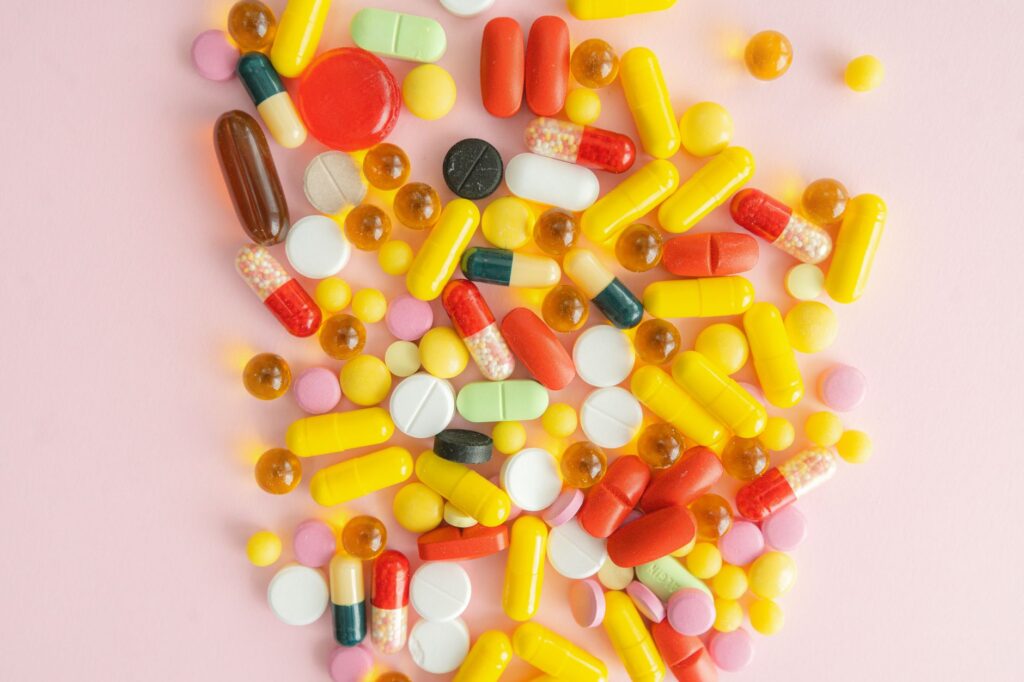 Verschiedene bunte Vitamintabletten auf einer weißen Fläche verstreut