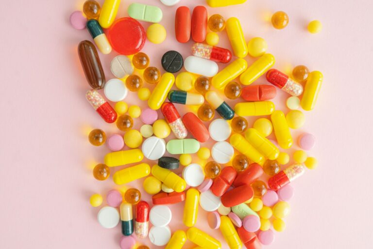 Verschiedene bunte Vitamintabletten auf einer weißen Fläche verstreut