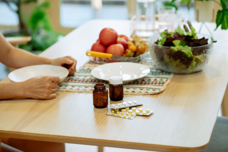 Frisches Gemüse und Obst neben einzelnen Supplement-Dosen auf einer Küchenablage