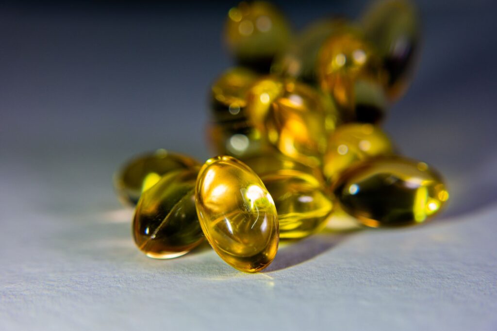 Sonnenlicht fällt auf eine Hand mit einer einzelnen Vitamin-D-Kapsel