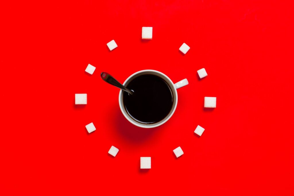 Zuckerwürfel und ein Löffel neben einer Tasse – Symbolbild für bewussten Umgang mit Zucker