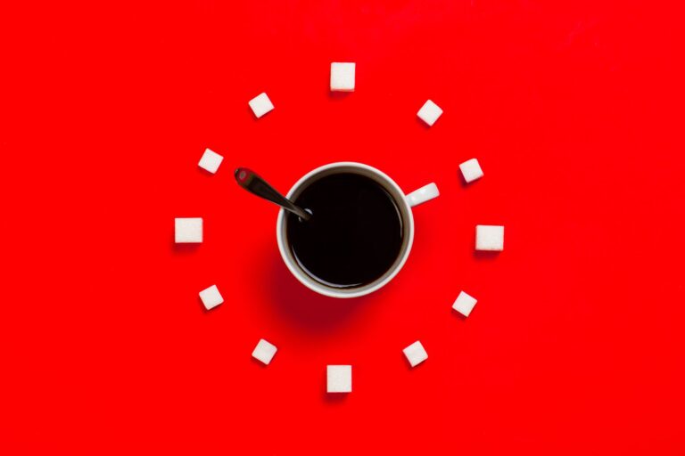 Zuckerwürfel und ein Löffel neben einer Tasse – Symbolbild für bewussten Umgang mit Zucker