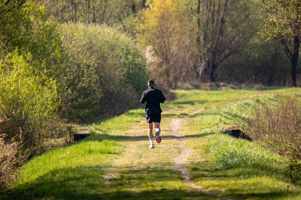 Freizeitläufer joggt auf einem grünen Naturweg – Laufen und Kniearthrose-Risiko
