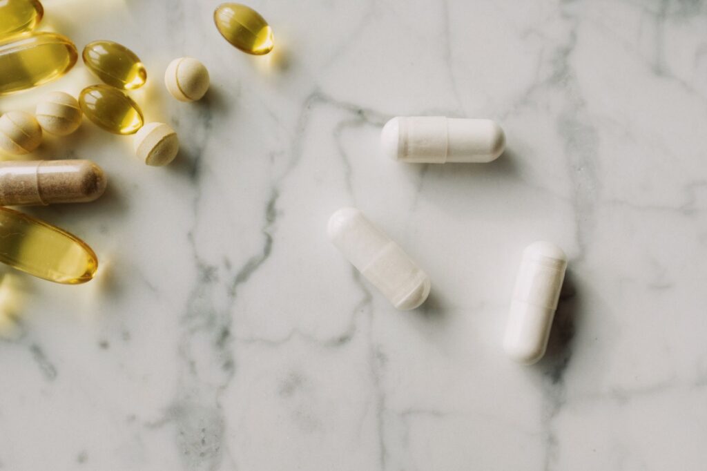 Verschiedene Nahrungsergaenzungs-Kapseln und Softgels auf einer Marmorflaeche