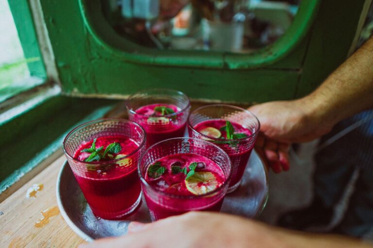 Vier Gläser frisch gepresster Rote-Bete-Saft mit Minze und Zitrone auf einem Tablett