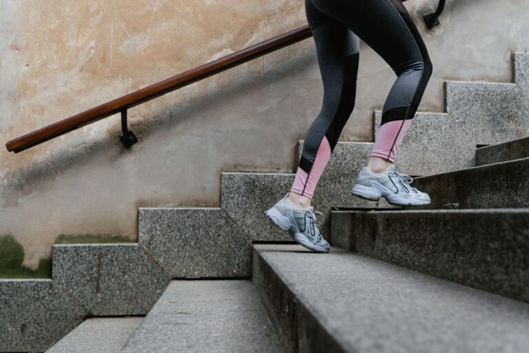 Frau in Sportleggings steigt zügig eine Steintreppe im Freien hinauf – Treppensteigen als Alltagstraining