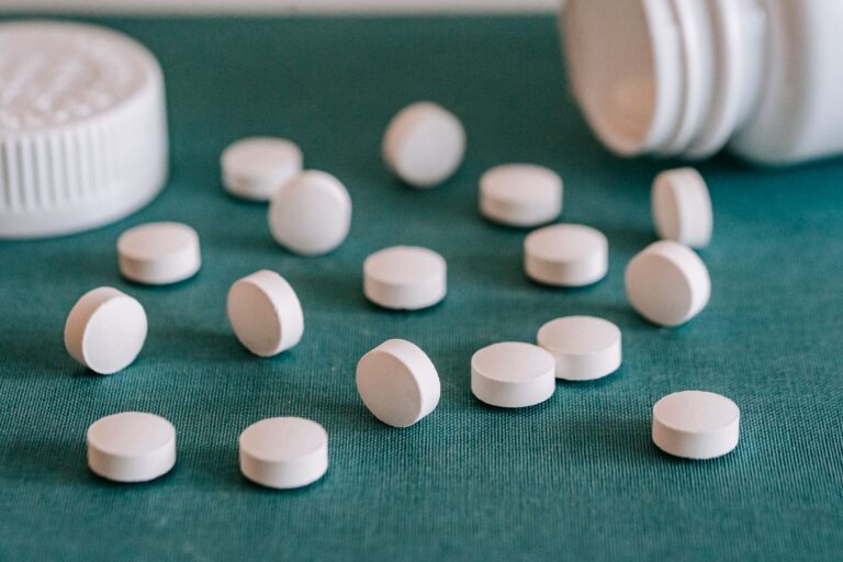 Weiße Tabletten aus einer umgekippten Dose auf grünem Untergrund – Symbolbild für hoch dosierte Vitamin-B6-Präparate