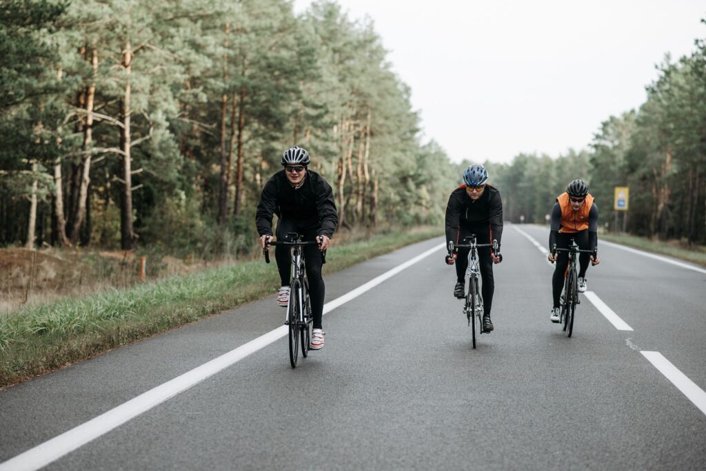 Drei Rennradfahrer auf einer Waldstraße – gebündeltes Wochenend-Training (Weekend Warrior)
