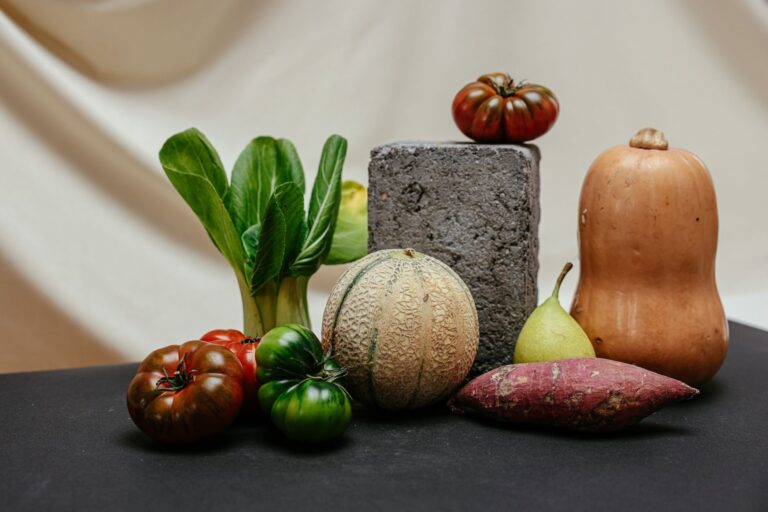 Verschiedene Gemüse- und Obstsorten nebeneinander auf einem Tisch: Pak Choi, Tomaten, Melone, Birne, Butternusskürbis und Süßkartoffel