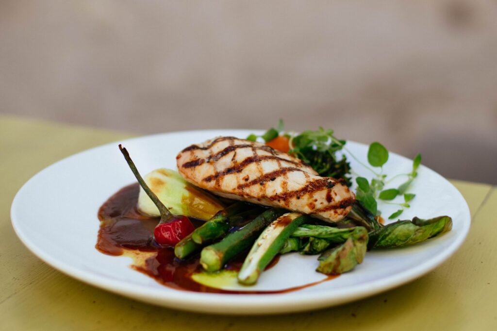 Gegrillte Hühnerbrust mit grünem Gemüse auf einem weißen Teller – proteinreiche Mahlzeit für Muskelerhalt im Kaloriendefizit