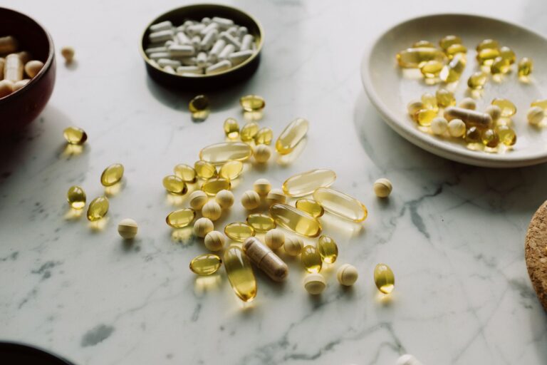 Verschiedene Nahrungsergänzungs-Kapseln und Tabletten auf einer hellen Marmorfläche